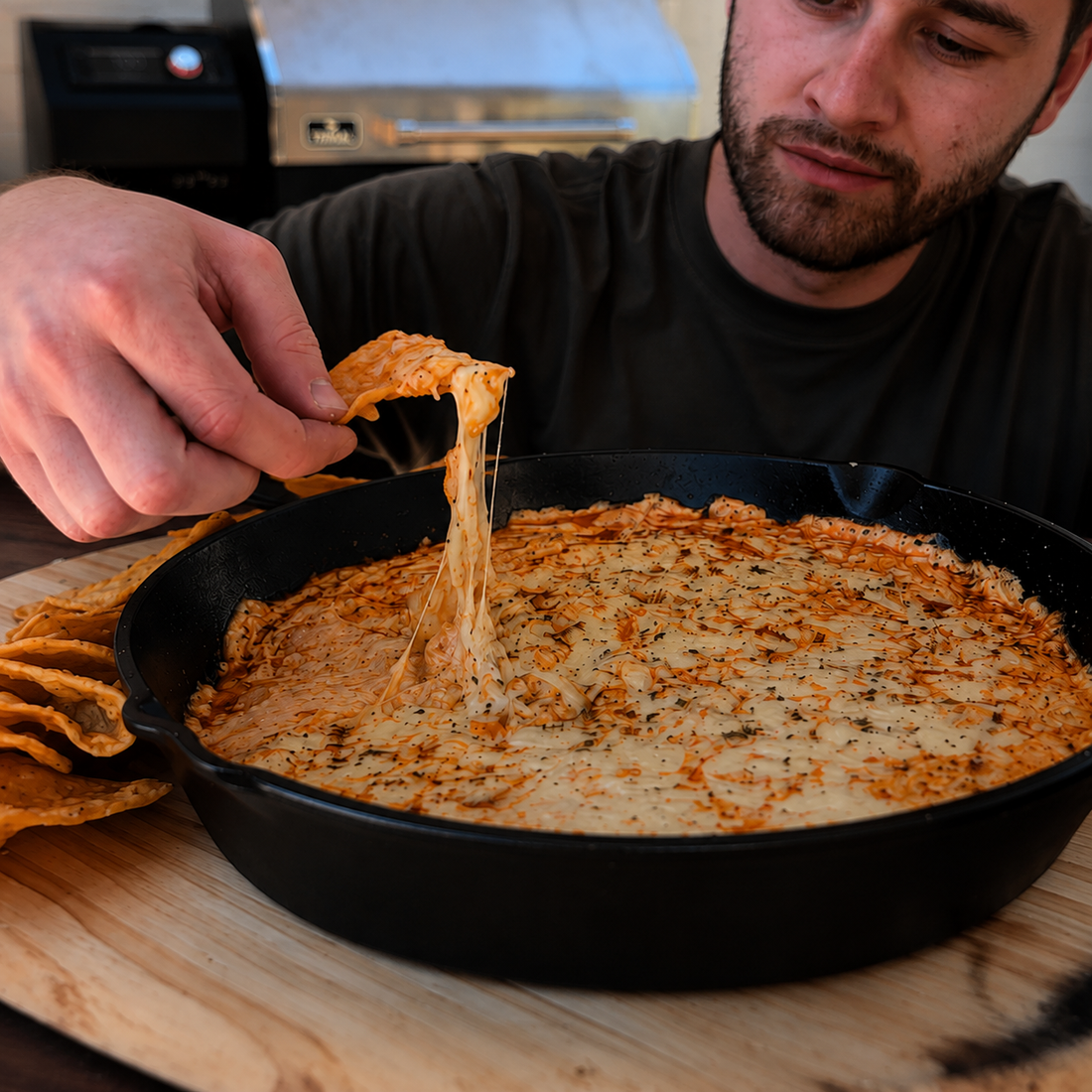Smoked Buffalo chicken dip with shredded BBQ chicken, melted cheese and Buffalo sauce in a cast-iron skillet