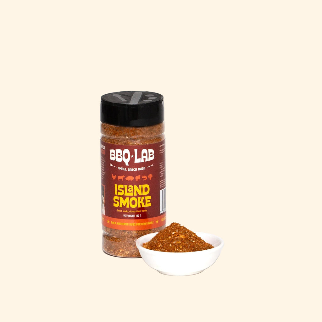 BBQ LAB Island Smoke BBQ rub bottle beside a bowl of the reddish-brown seasoning